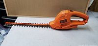 Side and top views of a Black & Decker orange electric hedge trimmer, shows overall condition and blade details.