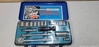 Blue metal case opened showing ratchet socket set with ratchet, sockets, extensions, and adapters.