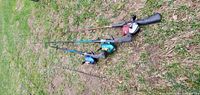 Four fishing rods laid out on grass with attached reels in different colors, showing condition and variety.