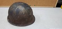 Front angle view of a heavily worn WWII military helmet showing rust and patina.
