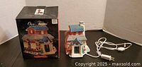 Photo showing the Christmas village house next to its original Our Town box, with visible electrical cord.