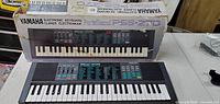 Yamaha Porta Sound PSS-270 keyboard with original box on table, shows full face and keys with control panel and labeling.