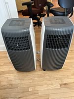 Two grey SPT portable air conditioners side by side showing front vents and overall unit shape.