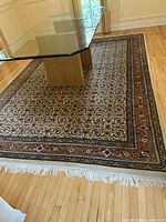 Full view of the 8x12 wool floral area rug laid out in a room under a glass table