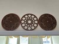 Front view of the three round wooden wall art pieces mounted on the wall above a doorframe, showing all three distinct geometric designs.