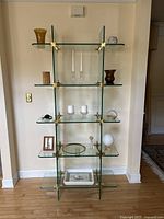 Display shelf with assorted decorative items showing shelf layout, clear glass, and brass connectors