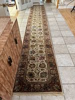 Full-length view of runner rug laid on tile floor showing entire rug and fringed ends.