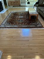 Full view of the rectangular rug laid out in living space under a coffee table on hardwood floor