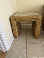 Side view of one square wicker side table showing natural wicker weave and glass top.