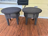 Photo of two round dark brown wicker patio tables side by side on wooden deck, showing size comparison and wicker texture.