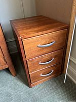 Brown wooden 3-drawer filing cabinet with metal handles, showing surface wear and nicks