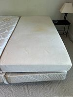 Twin Tempur memory foam mattress on box spring, off-white color, showing central stains on mattress surface