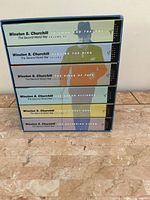 Side view of the set showing the spines of the six volumes with distinct colored panels and titles.