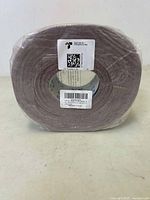 Front view of the sealed roll of 120 grit sandpaper wrapped in plastic showing label and packaging.