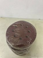 Stack of sanding discs wrapped in plastic showing the 8 holes and reddish-brown abrasive surface