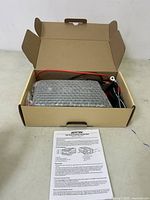 Box open with inverter wrapped in bubble wrap and cables beside it. Installation manual placed in front of the box.
