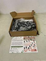 Box containing plastic-wrapped black metal garage hooks and an informational flyer.