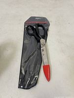 Full view of Crescent Wiss W20 industrial scissors in original sealed packaging showing black handles and red blade tip cover.