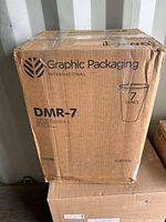 Cardboard box with Graphic Packaging International branding and DMR-7 model label, showing '7 ounce' cup sizing.