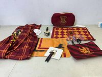 Lot overview showing Gryffindor pants, zippered bag, flags, keychain, pin, and collectible figure keychain.