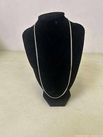 Silver curb chain displayed on a black mannequin, showing full length and overall style.