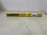 Full length photo of sealed yellow package of Tooloom mild steel TIG welding rods ER70S-6 placed on a flat surface.