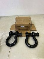Two black 3/4 inch D ring shackles displayed in front of original brown box packaging with Ohuhu branding.
