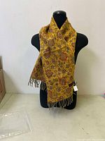 Front view of the scarf draped on a mannequin showing the full length and the yellow base with colorful Mafla patterns.