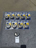 Top view photo showing 10 individual Simply Self Storage disc padlocks arranged neatly on a grey surface, 9 in blister packs and 1 unpackaged with key attached.