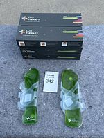 Six stacked boxes and one pair of green gel foot packs displayed with clear plastic straps, new in box packaging visible.