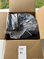Box containing curved black plastic landscaping edging pieces wrapped in plastic.