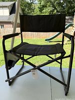 Front view of the black camping chair showing padded seat, backrest, armrests, and metal frame.