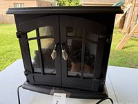 Front view of black electric fireplace with glass double doors and handles.