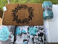 Photo showing brown coir doormat with black floral wreath design and three blue rose themed wall art panels