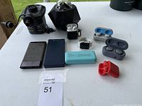 Full view of electronics lot including power bank, smart watch, wireless earbuds, phones, electric pump, and black electronic device.