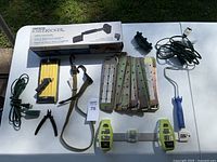 Overview photo of the lot including Roberts Knee Kicker carpet stretcher in its packaging, metal brackets, tools, and wires.