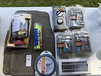 Lot of home items including boxed Korky toilet valve kit, Schlage door lockset, Kwikset door locks, garden hose, thermal cooling towel, and a white vent cover grille.