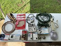 Full assortment of home improvement tools and supplies displayed on table outdoors including wiring, switches, and plumbing parts.
