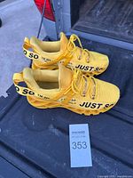 Pair of bright yellow Just So So knit sneakers with lace-up closure and brand name printed on the upper and heel band.