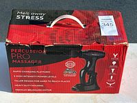Closed red retail box with product image and info on Percussion Pro Massager, showing features like rapid charge and multiple intensity levels.