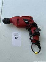 View of the whole red electric power drill showing cord and drill tip.