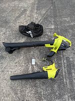 Ryobi 40-volt cordless leaf blower with wheel attachment, handheld yellow Ryobi blower, and leaf collection bag on concrete surface.