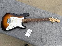 Full view of the Squier Stratocaster electric guitar showing the body with sunburst finish, white pickguard, and rosewood fingerboard.