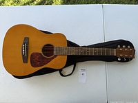 Front view of Yamaha acoustic guitar showing natural wood finish, pickguard, bridge and strings.