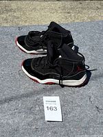 Pair of black and red Air Jordan 11 youth sneakers, side view showing overall condition and design.