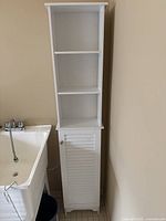 Full front view of white slim storage cabinet beside utility sink