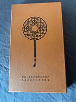 Closed orange box top showing printed fan motif and Chinese characters