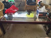 Full view of coffee table showing wood frame, glass top, legs, surrounding context