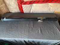 Full view of black cylindrical Flambeau fishing rod holder tube on surface