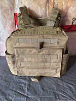 Front view of tan MOLLE tactical vest showing webbing and front pouch
